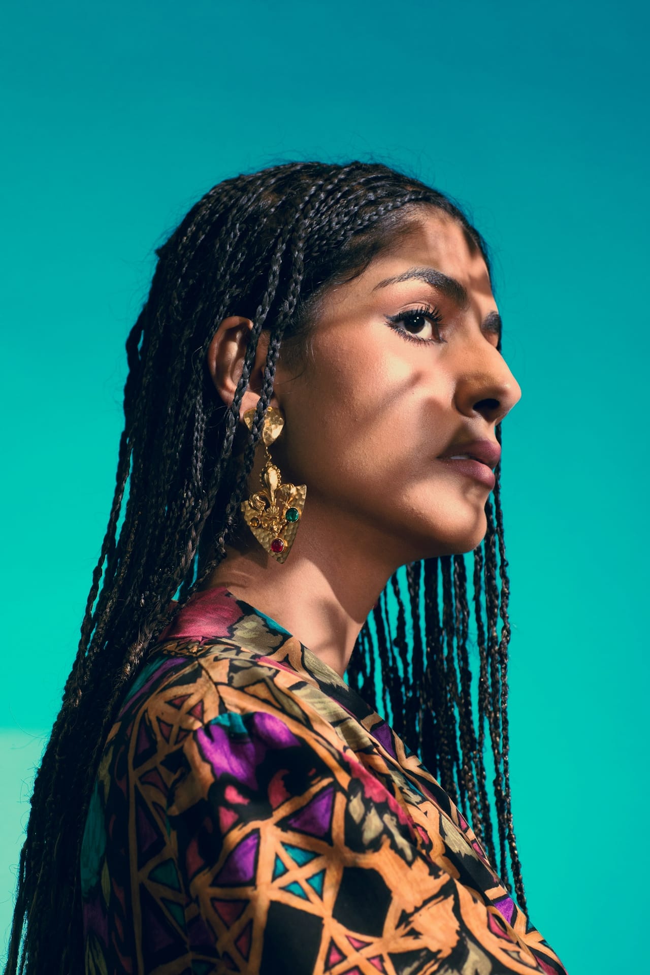 Portrait of a woman with braided hair against a turquoise background, from the Etc. Collective launch campaign